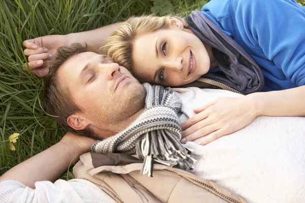 Ungt par liggande tillsammans på gräs — Stockfoto