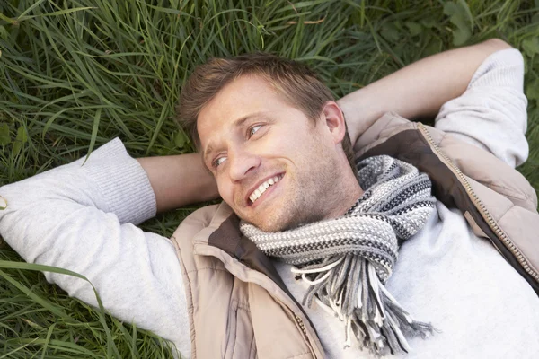 Mladý muž ležící na trávě sám — Stock fotografie