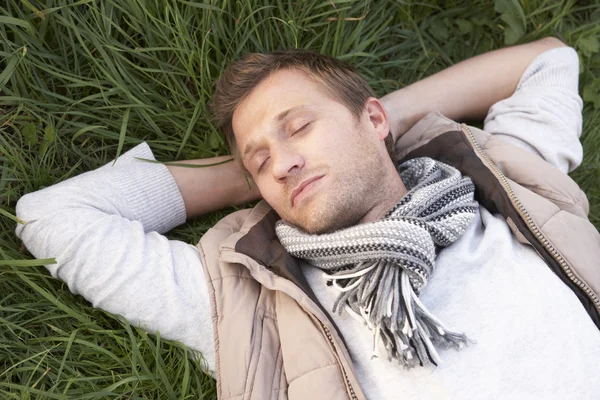 Молодой человек спит в одиночестве на траве — стоковое фото