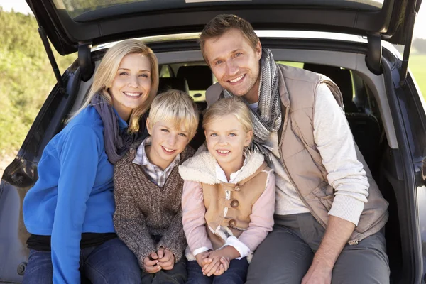 Young family pose together at rear of car — Stock Photo, Image