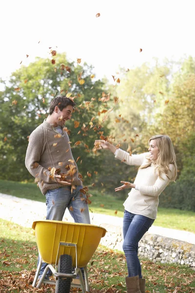 Young couple having fun with autumn leaves in garden — Stock Photo, Image