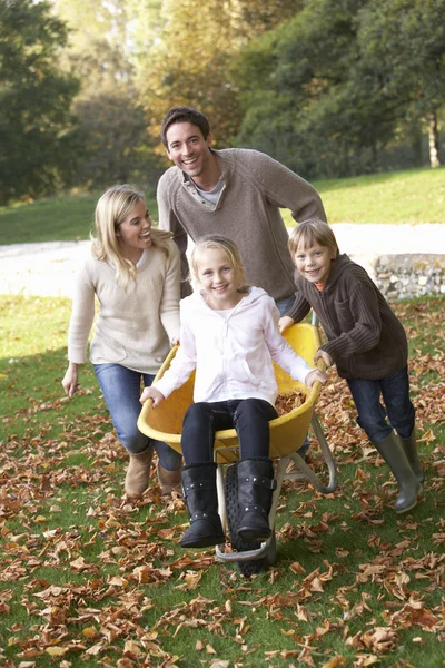 Familia divirtiéndose con hojas de otoño en el jardín —  Fotos de Stock