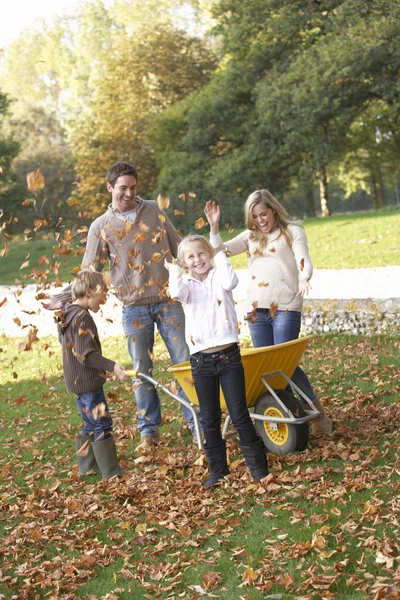 Family throwing autumn leaves into the air in garden — Stock Photo, Image