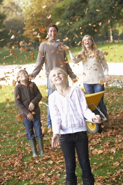 Famille jetant des feuilles d'automne dans l'air dans le jardin — Photo