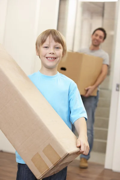 Niño con el hombre joven en el día en movimiento llevando caja de cartón —  Fotos de Stock