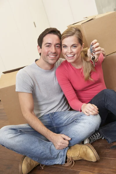 Jovem casal sentar no chão em torno de caixas segurando chave na mão — Fotografia de Stock