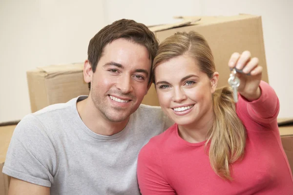 Young couple sit on the floor around boxes holding key in hand — Stock Photo, Image