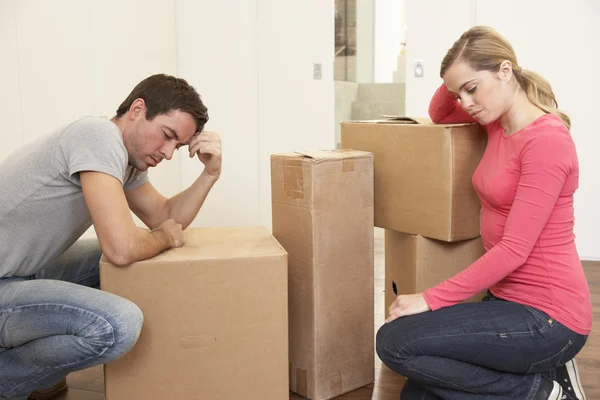 Young couple looking upset among boxes — Stock Photo, Image