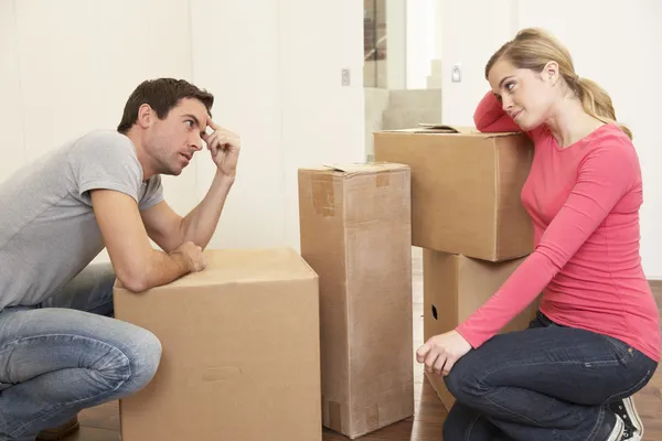 Young couple looking upset among boxes — Stock Photo, Image