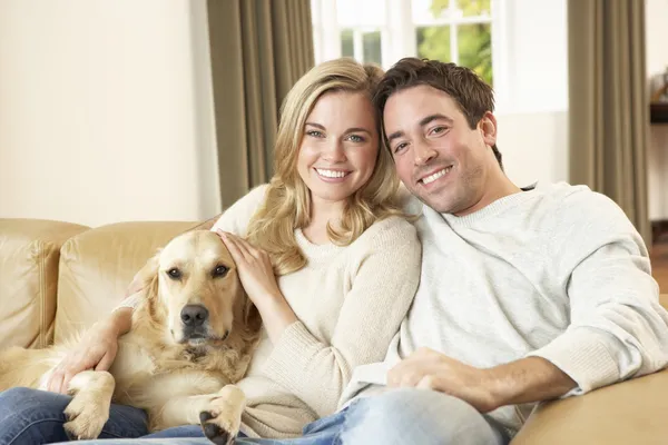 Młoda szczęśliwa para z psem na kanapie — Zdjęcie stockowe