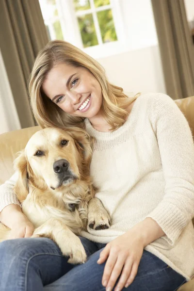 Young woman with dog sitting on sofa — Stock Photo, Image