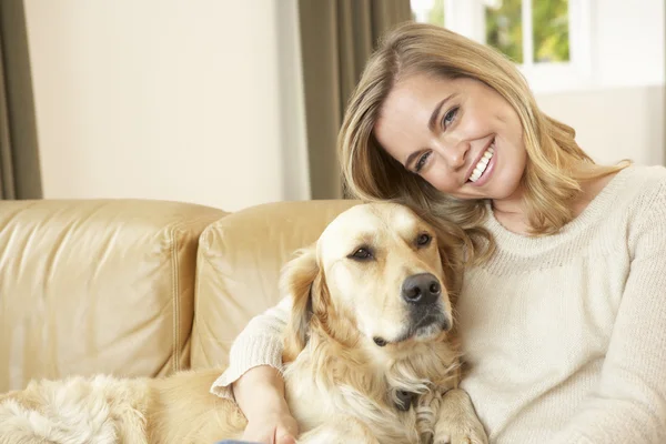 Ung kvinna med hund sitter på soffan — Stockfoto