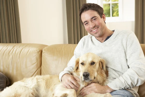 Jovem com cão sentado no sofá — Fotografia de Stock