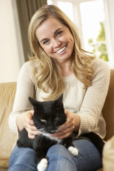 Glückliche junge Frau mit Katze auf Sofa sitzend — Stockfoto
