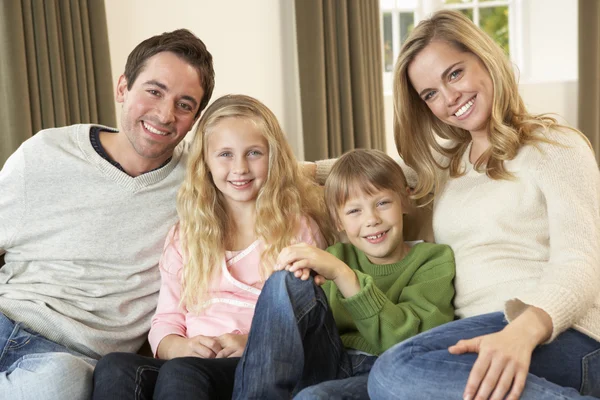Счастливая молодая семья сидит на диване — стоковое фото