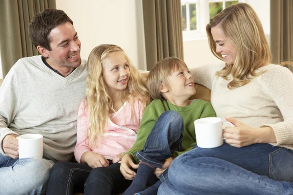 Jovem família feliz sentado e falando no sofá — Fotografia de Stock