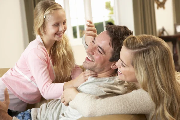 Glad ung familj spelar tillsammans på soffa — Stockfoto
