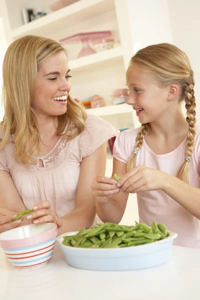 Ung kvinna med barn dela ärta i köket — Stockfoto