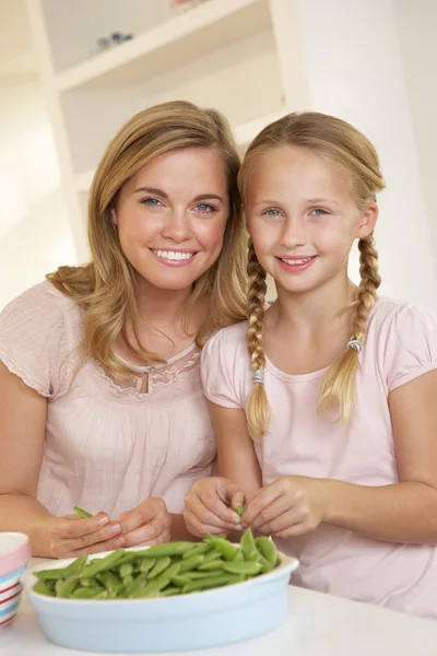 台所でエンドウ豆の分割の子供を持つ若い女 — ストック写真