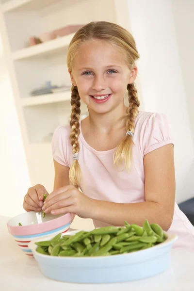 幸せな女の子の台所でエンドウ豆の分割 — ストック写真