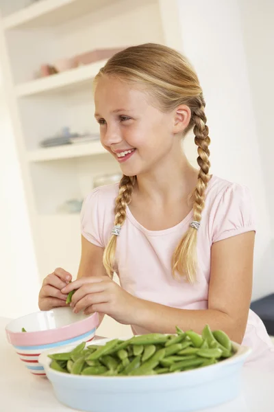 Glückliches Mädchen, das Erbsen in der Küche teilt — Stockfoto