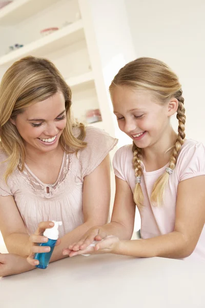 Mor sätter rengöringsmedel på unga flickans händer — Stockfoto