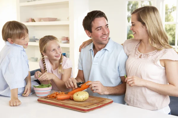 Família feliz descascando legumes na cozinha — Fotografia de Stock