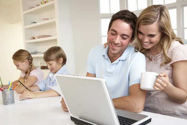 Jovem família feliz olhando e lendo um computador portátil — Fotografia de Stock