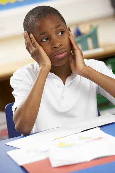 Olycklig skolpojke studerar i klassrummet — Stockfoto