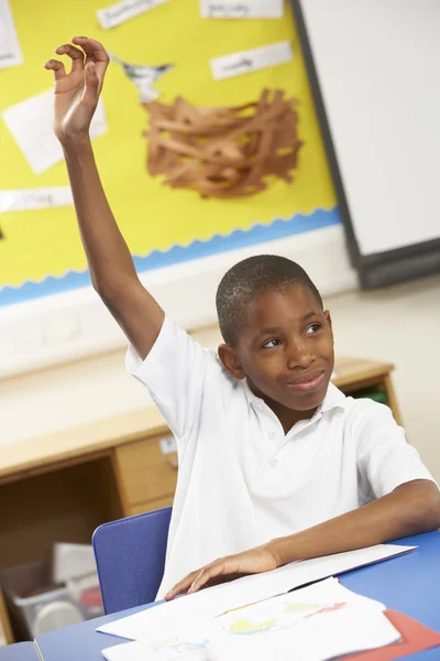 Écolier levant la main dans la salle de classe — Photo