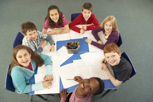 Вид сверху на школьников, работающих вместе за рабочим столом — стоковое фото