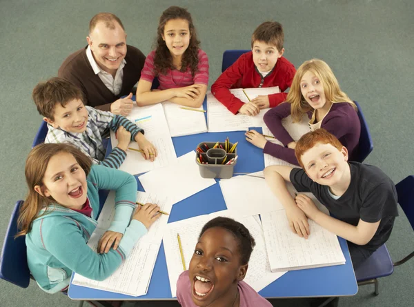 Школьники, работающие вместе за столом с учителем — стоковое фото