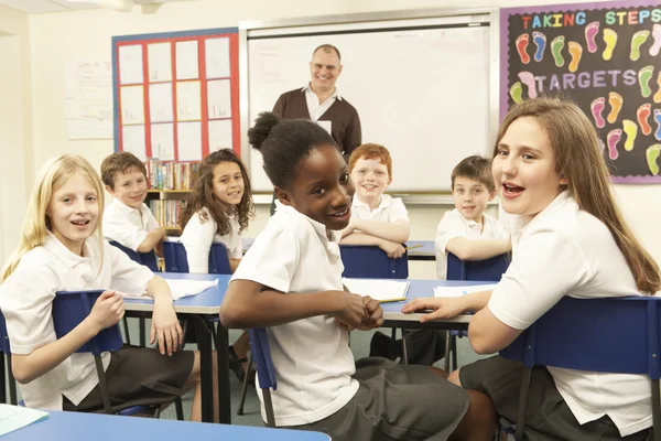 Crianças em idade escolar estudando na sala de aula com professor — Fotografia de Stock