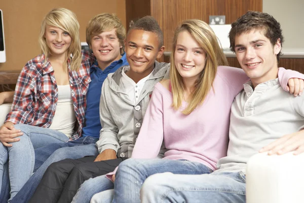 Groep van jeugdvrienden zittend op de Bank thuis — Stockfoto
