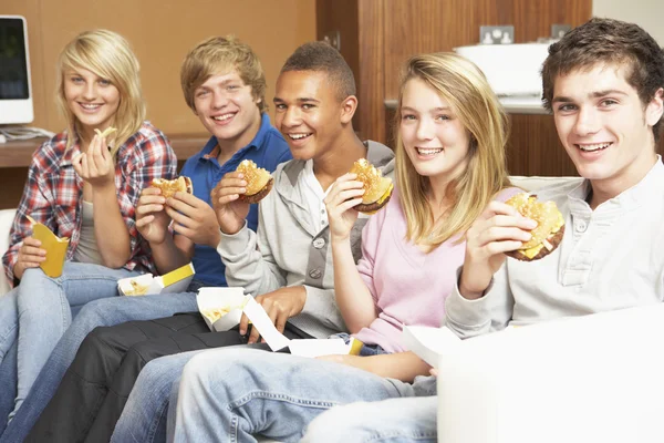 Gruppe von Teenagerfreunden sitzt zu Hause auf dem Sofa und isst schnell foo — Stockfoto
