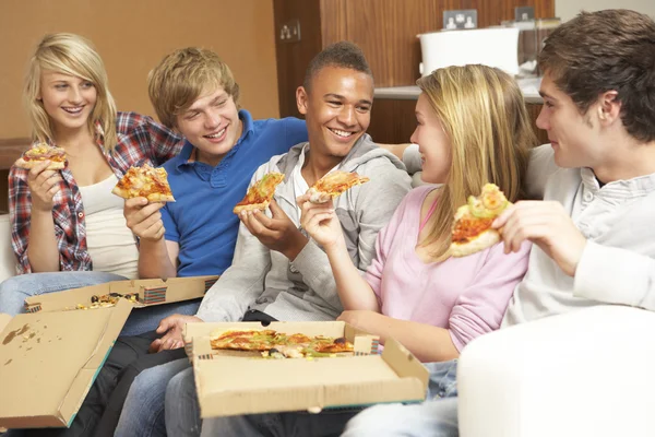 Группа друзей-подростков, сидящих дома на диване и поедающих пиццу — стоковое фото