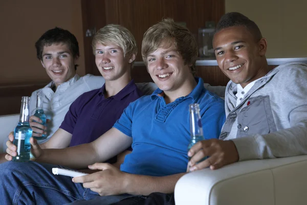 Grupo de meninos adolescentes sentados no sofá em casa assistindo a beber — Fotografia de Stock
