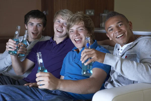 集团的十几岁的男孩坐在沙发上回家看着喝 — 图库照片