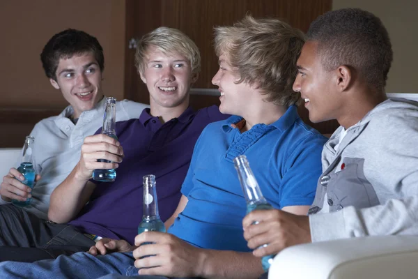 Grupo de meninos adolescentes sentados no sofá em casa assistindo a beber — Fotografia de Stock