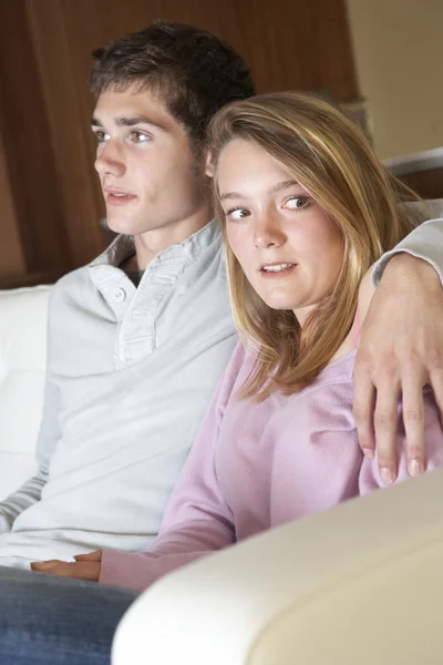 त्रासदायक दिसत किशोरवयीन मुलगी बसणे पर सोफा पर घर साथ बॉयफ्री स्टॉक फोटो