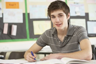 Male Teenage Student Studying In Classroom clipart