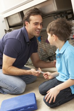 Son Helping Father To Mend Sink In Kitchen clipart