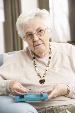 Senior Woman Sorting Medication Using Organiser At Home clipart