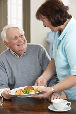 Senior Man Being Served Meal By Carer clipart