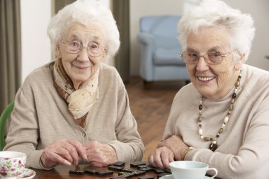 Two Senior Women Playing Dominoes At Day Care Centre clipart