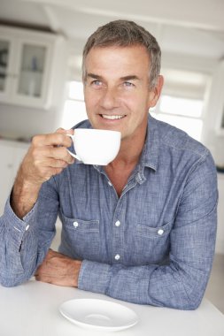 Mid age man with coffee at home clipart