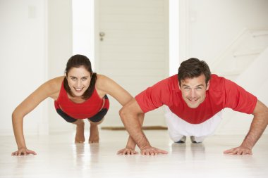 Couple doing push-ups in home gym clipart