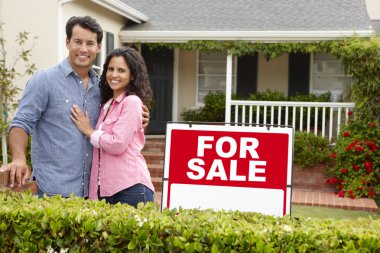 Hispanic couple outside home with for sale sign clipart