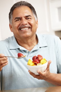 Senior man eating fruit clipart