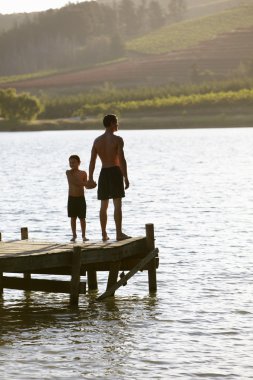 Young man with child at sunset clipart